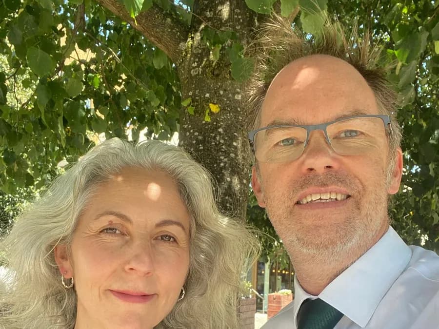Kate and Will Sopwith smiling together under a tree on a sunny day